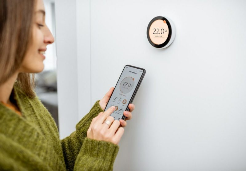 Woman Adjusting Thermostat 1200x837
